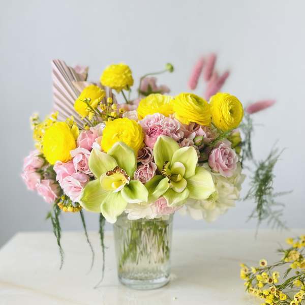 Pink and yellow flower bouquet in a clear glass vase
