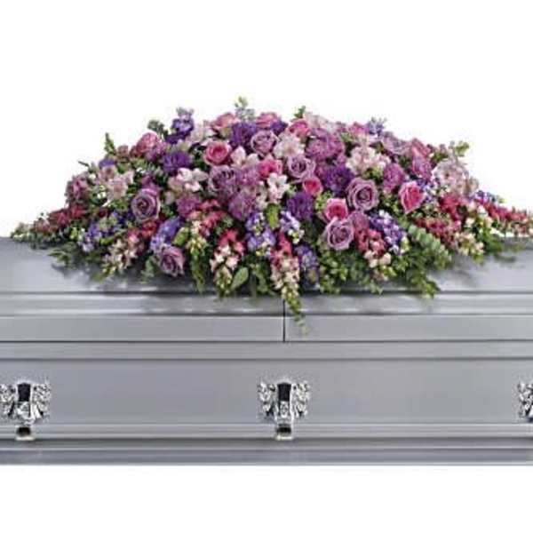 Long pink and purple casket spray arrangement on a silver casket
