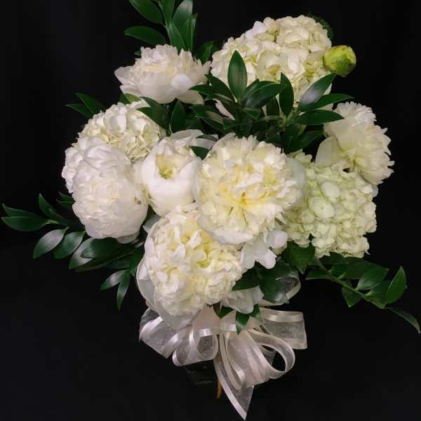 White floral bouquet with green foliage and a ribbon bow