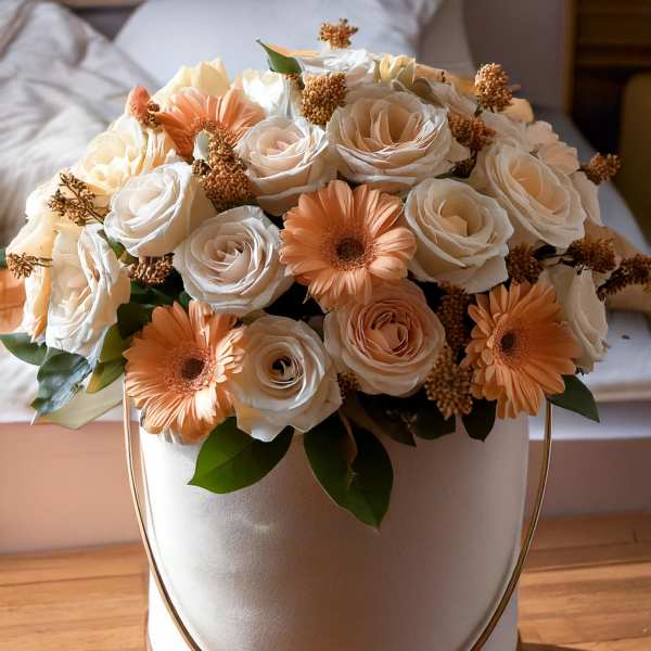 Cream and peach roses with gerbera daisies in a round hatbox