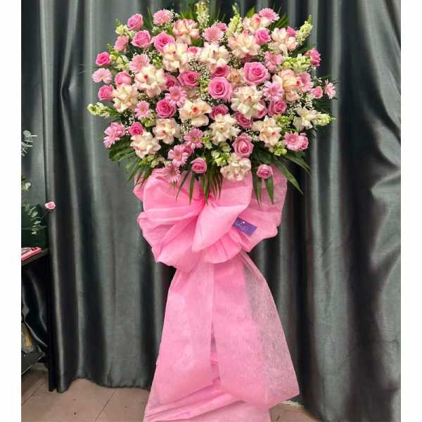 Pink and white floral standing spray with a large pink bow