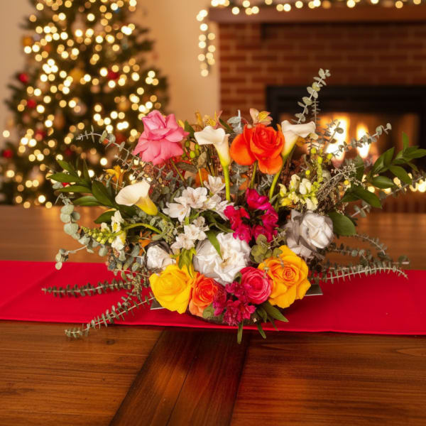 Mixed bouquet of roses and calla lilies on a table with holiday lights in the background