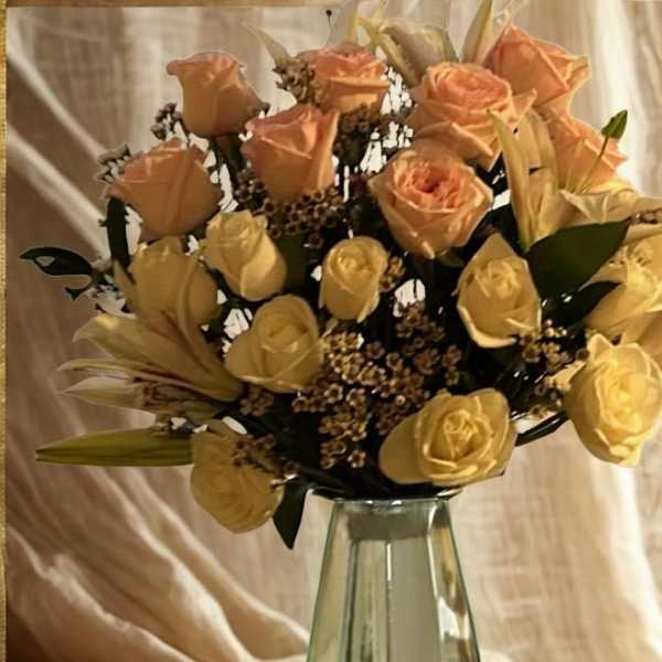 Peach and yellow roses arranged in a clear glass vase