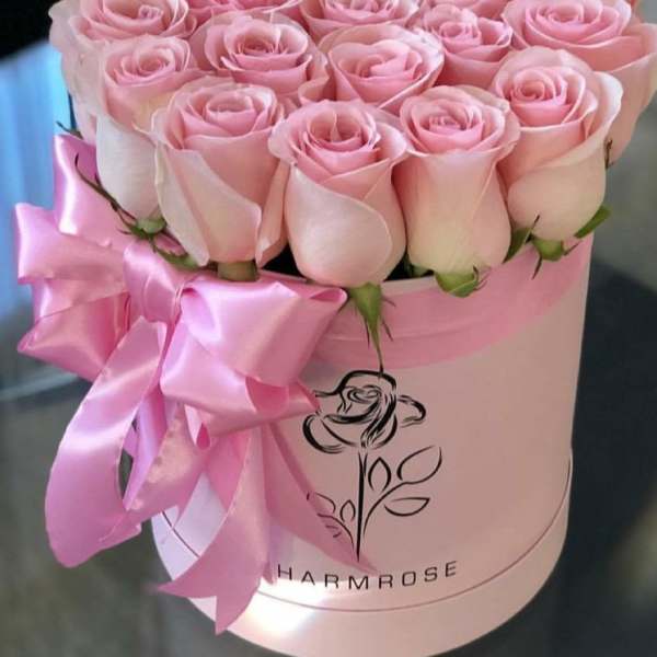 Pink roses arranged in a round hat box with a satin ribbon