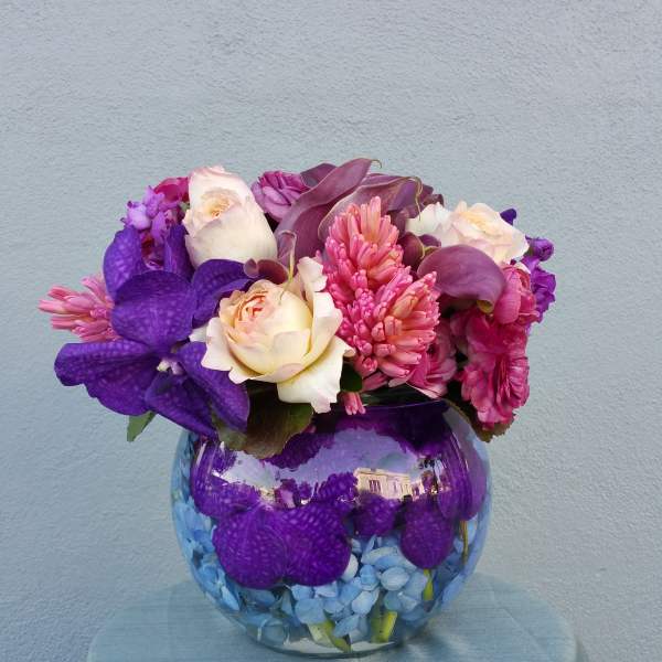 Purple and pink floral arrangement in a round glass vase