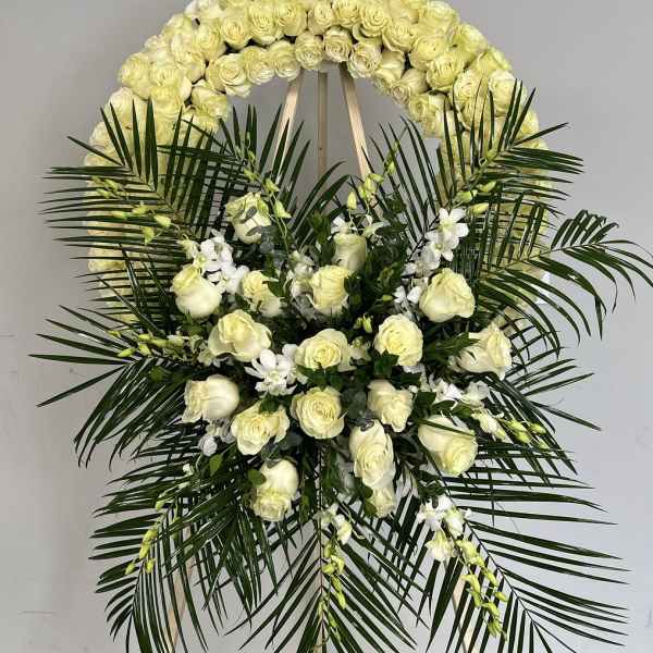 White rose funeral wreath with palm fronds and white orchids