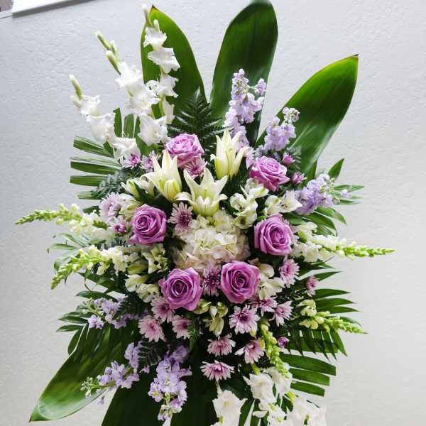 Standing floral spray with purple roses, white lilies, and lavender blooms