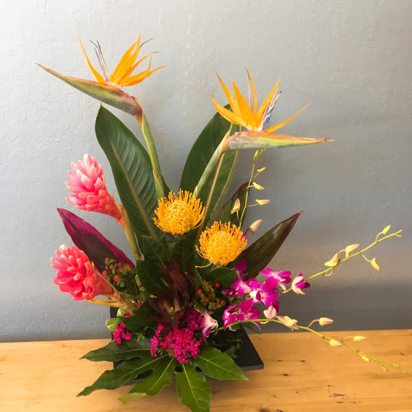 Tropical flower arrangement with orange bird-of-paradise and pink blooms in a black container