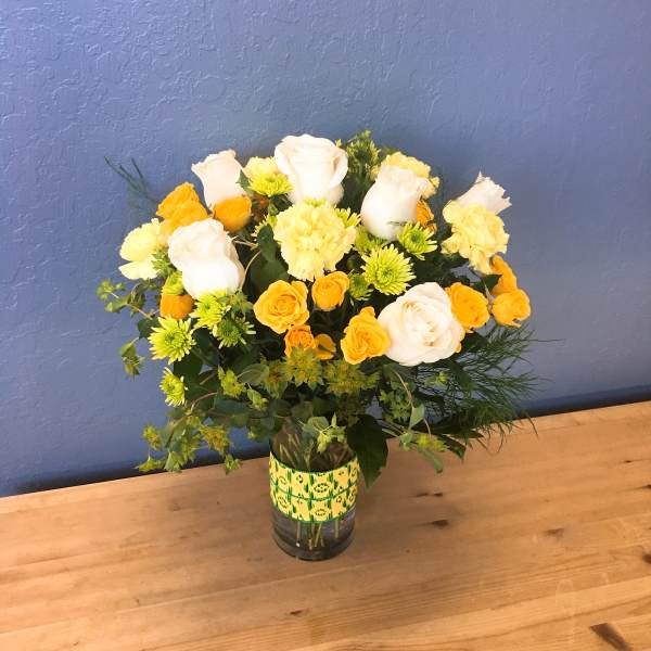 Bouquet of white roses and yellow flowers in a glass vase