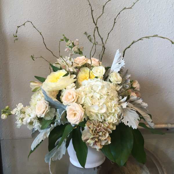 Cream and blush floral arrangement in a white vase with tall curly branches