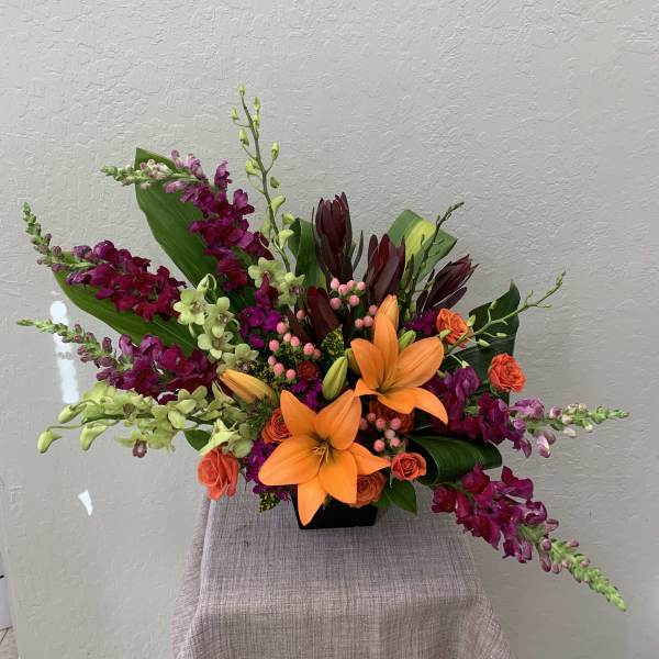 Orange lilies and magenta orchids in a black vase