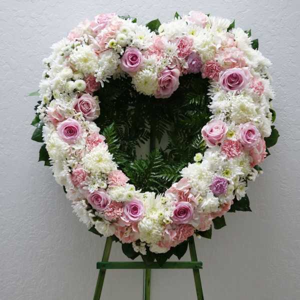 Heart-shaped floral wreath with pink and white flowers on an easel