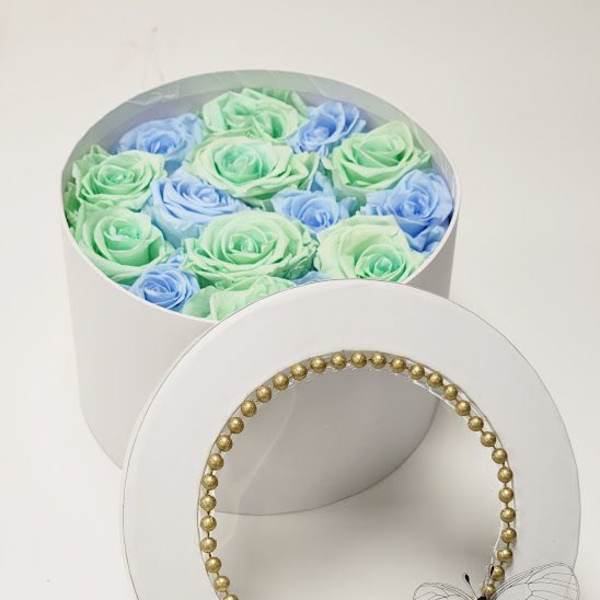 Round box of pastel roses with a gold beaded lid and butterfly accent