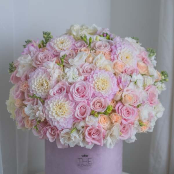 Round pastel bouquet of pink and white roses in a lavender box