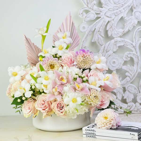 Pastel flower arrangement in a white bowl with roses and white blooms