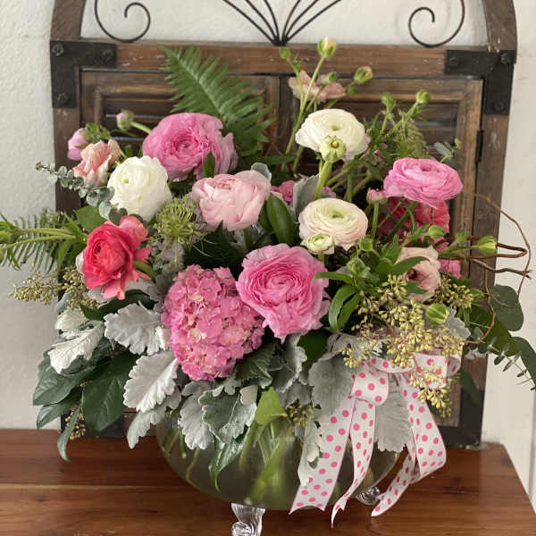 Pink and white flower arrangement in a glass vase with a polka-dot ribbon
