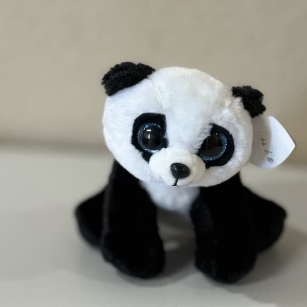 Small black-and-white plush panda toy sitting on a plain surface