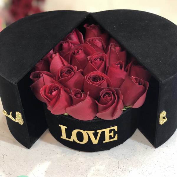 Red roses in a black hatbox with gold "LOVE" lettering