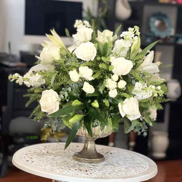 White rose arrangement in a silver pedestal vase