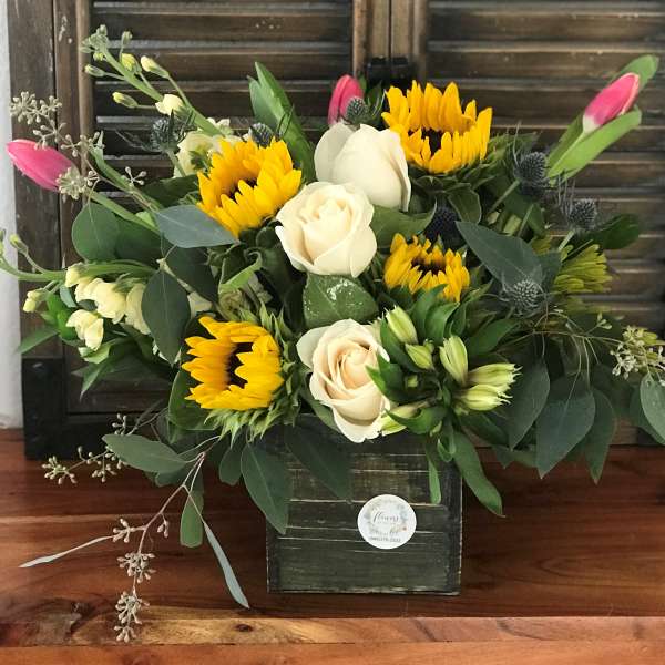 Bouquet of yellow sunflowers and cream roses in a dark box vase