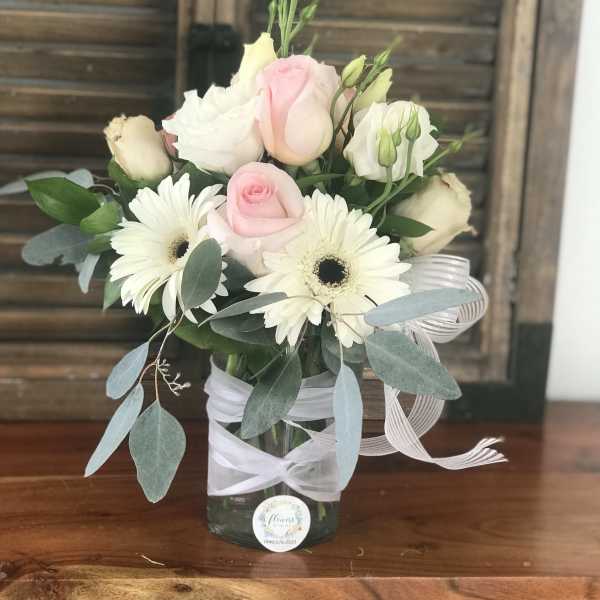 Pink and white roses with white daisies in a glass vase