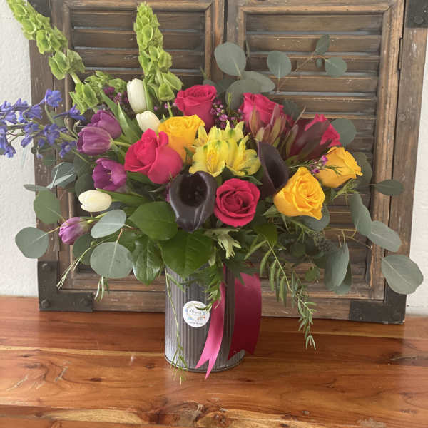 Mixed bouquet of roses, tulips, and calla lilies in a metal vase
