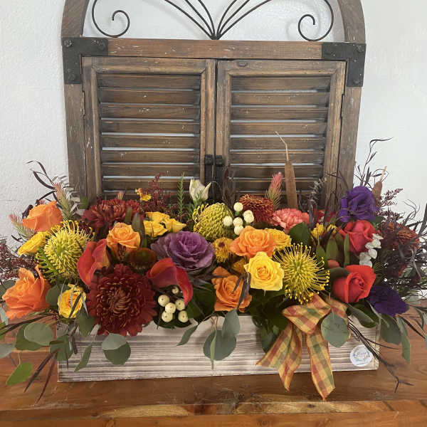 Colorful mixed flower arrangement in a wooden container with a plaid ribbon
