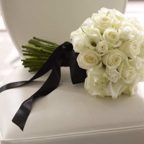 White rose bouquet with black ribbon on a white chair