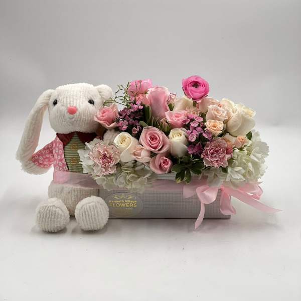 Pink and white flower arrangement with a knitted bunny plush in a box