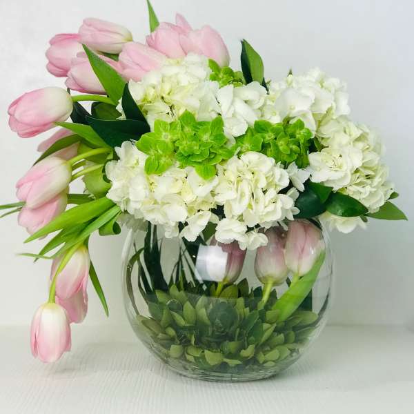 Pink tulips and white hydrangeas in a round glass vase