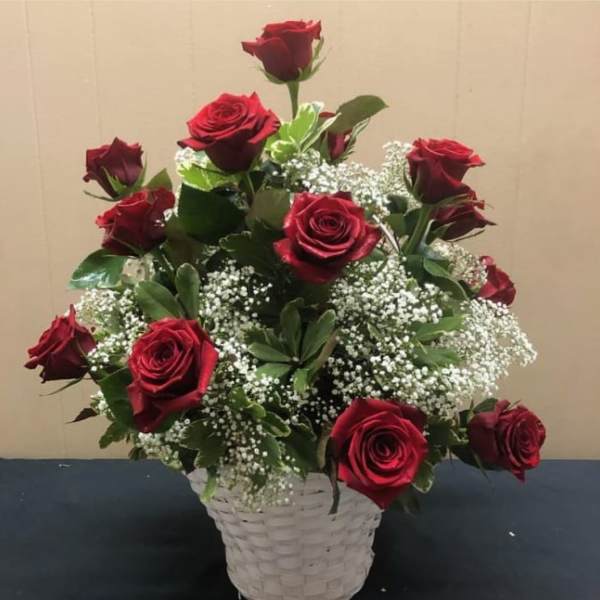 Red roses arranged in a white basket with baby's breath