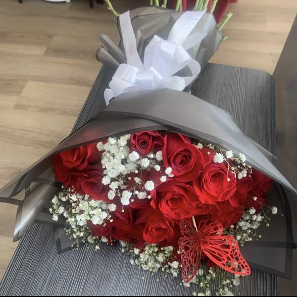 Bouquet of red roses with white baby's breath wrapped in gray paper
