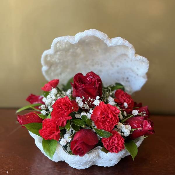 Red roses and carnations in a white shell-shaped basket