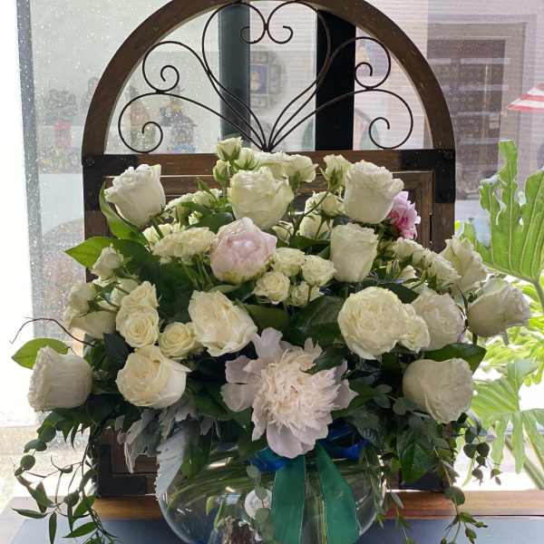 White rose arrangement in a glass vase with pink blooms and greenery