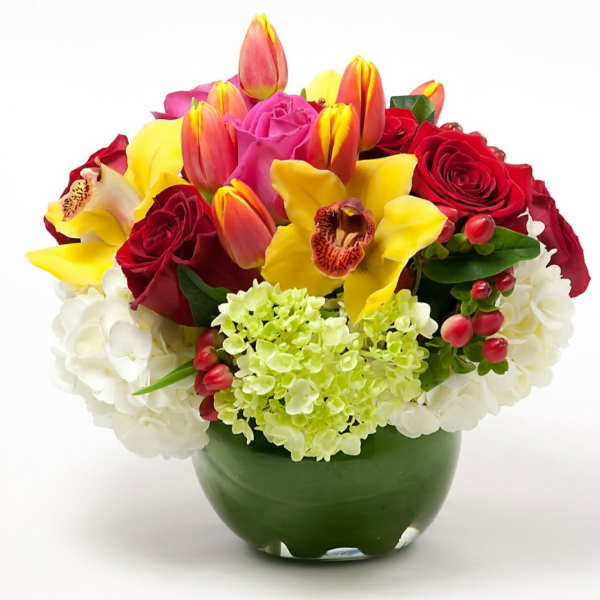 Mixed bouquet of roses, tulips, orchids, and hydrangeas in a green vase