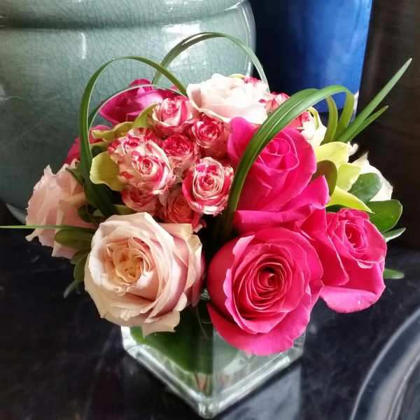Pink and blush roses arranged in a clear square vase