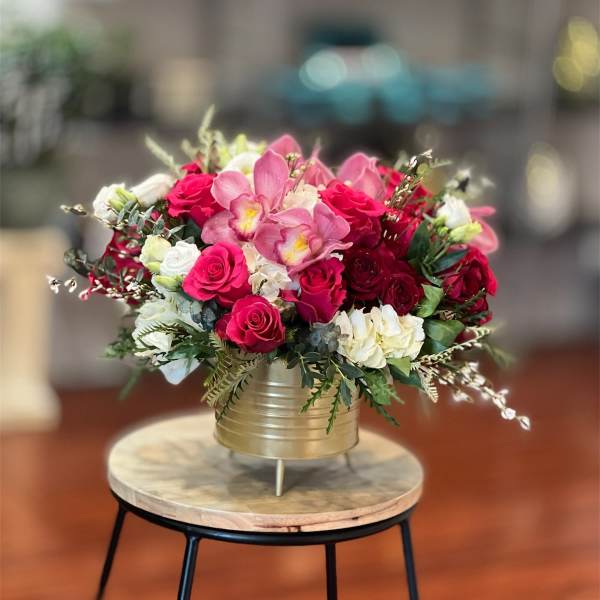 Pink and red rose bouquet in a gold vase on a small table