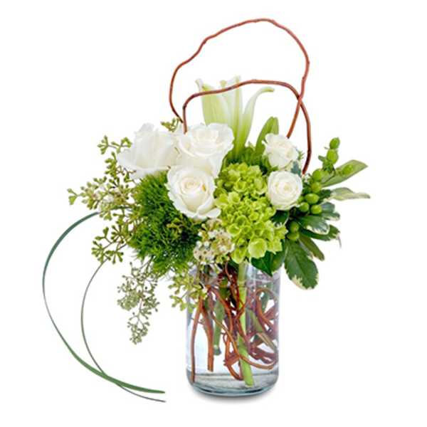 White roses and green flowers arranged in a glass vase with curly branches