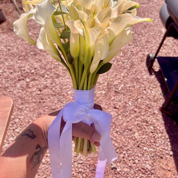Bouquet of white calla lilies tied with a white ribbon