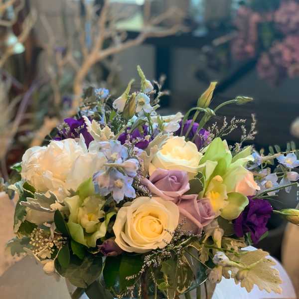 Mixed bouquet of white, lavender, and purple flowers in a glass vase