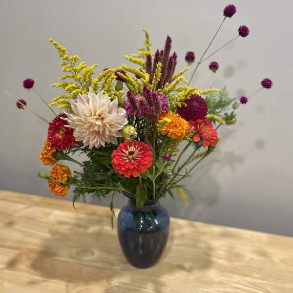 Mixed bouquet of colorful flowers in a blue glass vase