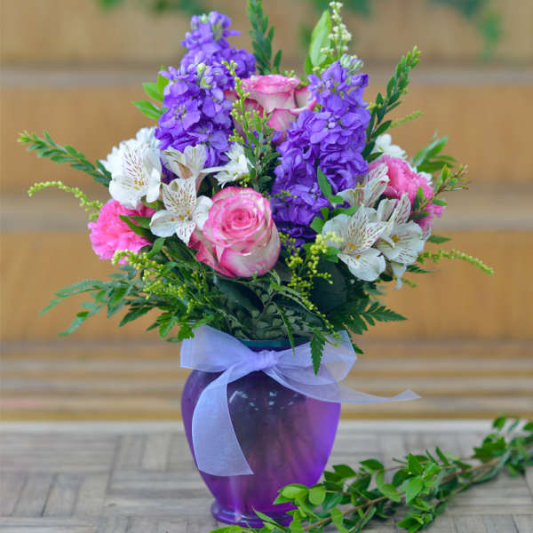 Pink and purple mixed bouquet in a purple vase with a ribbon