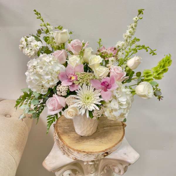 Pink and white roses with orchids and hydrangeas in a white vase