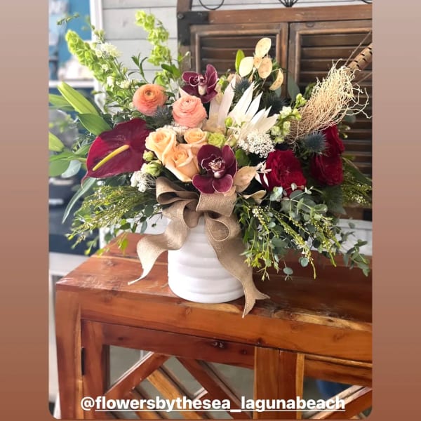 Mixed bouquet in a white vase with roses, orchids, and calla lilies