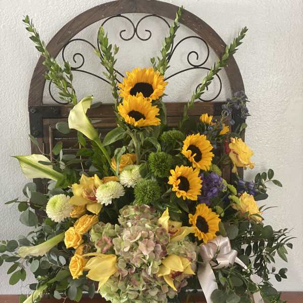 Mixed floral arrangement with sunflowers, lilies, and hydrangea in a metal container