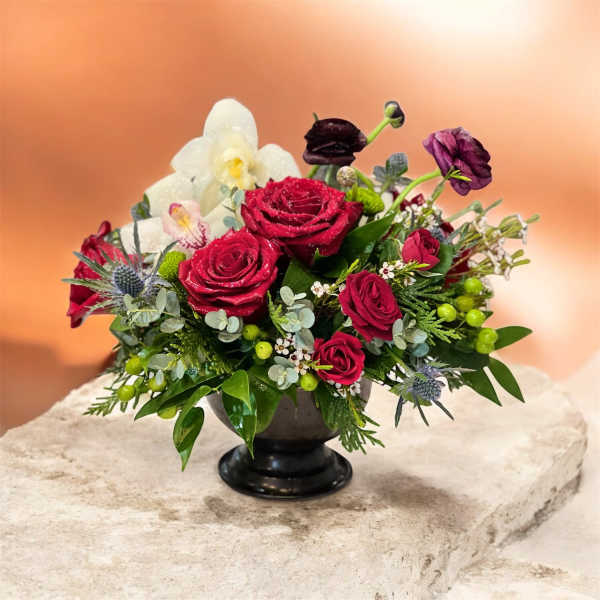 Red roses and white orchids in a black pedestal vase