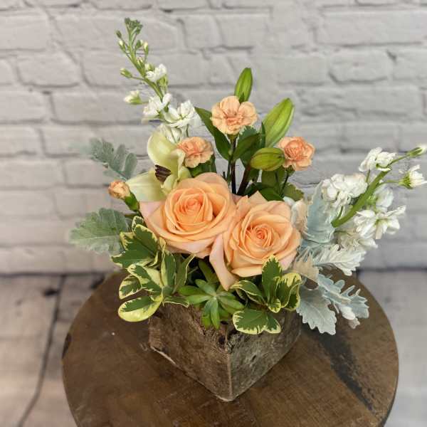 Peach roses and white flowers in a square rustic container