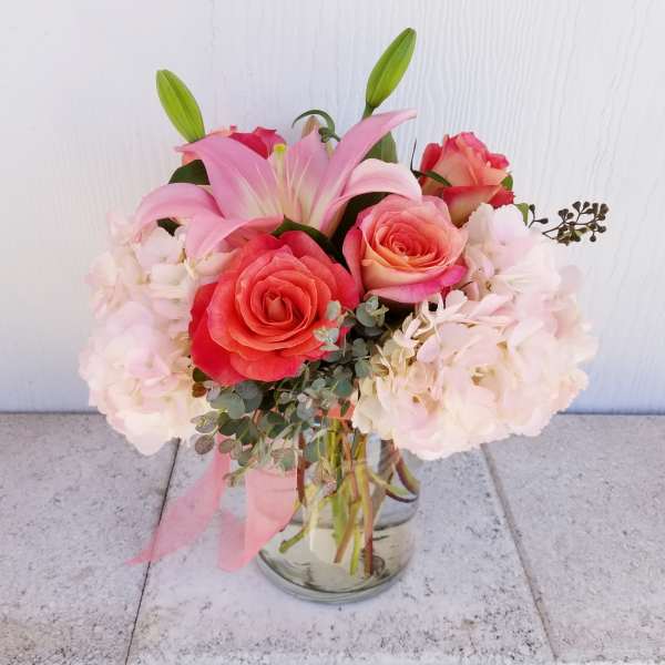 Pink lilies and roses arranged in a glass vase