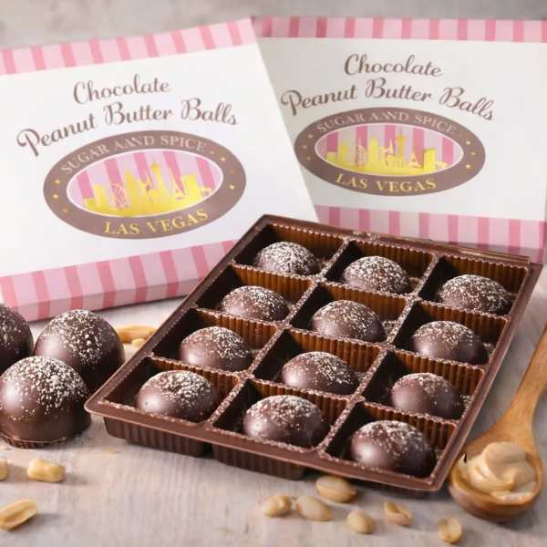 Box of chocolate peanut butter balls with open tray of truffles and scattered peanuts