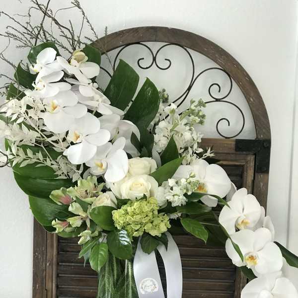 White orchid and rose arrangement in a glass vase with green accents